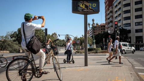 Varias personas fotografían un termómetro que marca 47 grados, este viernes en Valencia. EFE/Biel Aliño