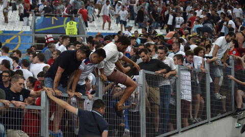 Ultras ingleses saltan una valla para huir de la zona de disturbios en las gradas del Vélodrome. /EFE