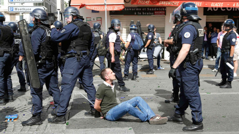 Un hincha esposado y sentado ante decenas de policías antidisturbios en Marsella. /REUTERS