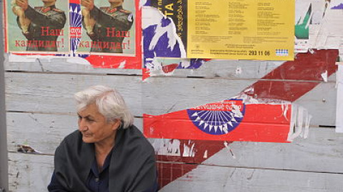 Una mujer descansa junto a carteles de propaganda electoral