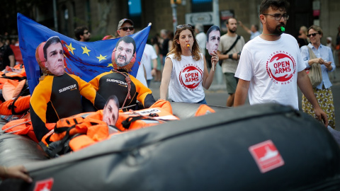 13/07/2019 - Manifestantes sostienen un bote hinchable con imágenes de las caras del presidente Pedro Sánchez y el ministro del Interior italiano, Matteo Salvini, en una protesta en Barcelona. / AFP - PAU BARRENA