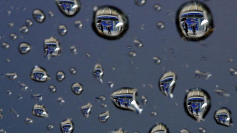 Una imagen rotada 180 grados, muestra gotas de lluvia que reflejan una pantalla que muestra información bursátil en Tokio, Japón. EFE/Franck Robichon