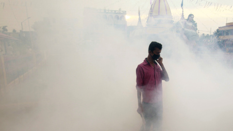 Un hombre cubre su cara mientras los trabajadores municipales fumigan el interior de un templo en Agartala, India. REUTERS/Jayanta Dey