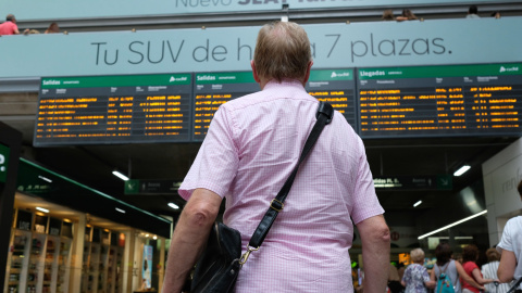 31/07/2019 - Un viajero espera frente a uno de los paneles de Salidas y Llegadas de la estación de trenes de Atocha