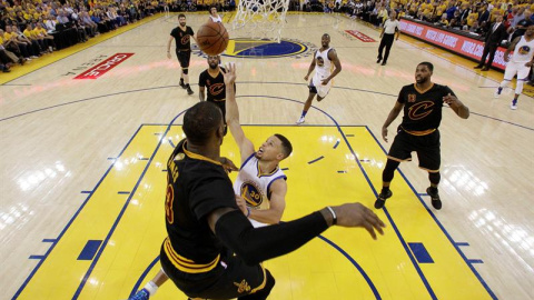 Stephen Curry (c) lucha por el balón con LeBron James en el quinto partido de la final.