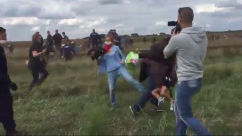 Petra László pone la zancadilla a un refugiado que corre con un niño en brazos en Röszke (Hungría).