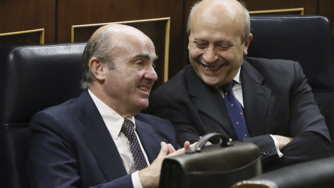 El ministro de Economía, Luis de Guindos, conversa con el titular de Cultura, José Ignacio Wert, durante la sesión de control al Gobierno en el pleno del Congreso. EFE/Fernando Alvarado