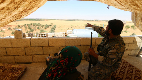 Un combatiente de las Fuerzas Democráticas Siria (SDF) problemas mientras está sentado en posición de mirar hacia fuera en el área rural occidental de Manbij, en Alepo gobernación, Siria, 13 de junio de 2016. REUTERS / Rodi Said