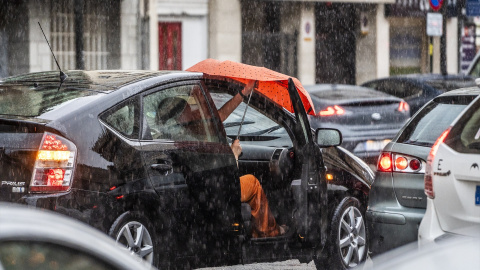 Una se sube a un coche bajo la lluvia, a 3 de julio de 2023, en Valencia, País Valencià.