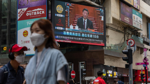 Ciudadanos caminan por una céntrica calle de Hong Kong junto a una pantalla gigante con el presidente de China, Xi Jinping, durante su intervención en el Congreso Nacional del Partido Comunista de China el 22 de octubre de 2022.