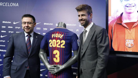 Piqué posa con el presidente del Barcelona, Josep María Bartomeu, tras ampliar su contrato. / ANDREU DALMAU (EFE)