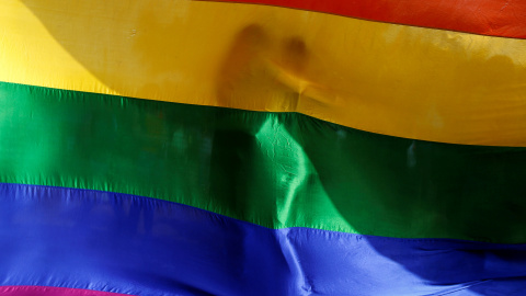 Dos personas se abrazan mutuamente tras una bandera arcoiris durante una vigilia en memoria de las víctimas del tiroteo del club gay Pulse de Orlando en Bombay, India. REUTERS/Danish Siddiqui