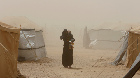 Una mujer que escapa de Faluya por el Estado Islámico cargando con su hijo durante una tormenta de arena al sur de Faluya, Iraq. REUTERS/Ahmed Saad