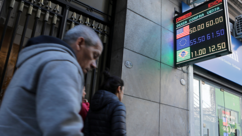 Los peatones pasan frente a un tablero electrónico que muestra los tipos de cambio en el distrito financiero de Buenos Aires | Reuters