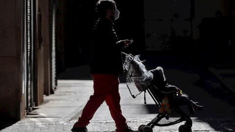 Un hombre pasea con un carrito de bebé por la ciudad de València.