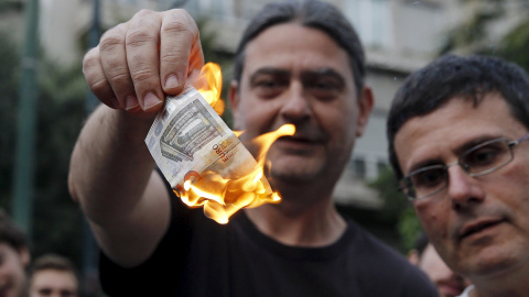 Dos personas queman unos billetes de euro en una manifestación anti austeridad frente a las oficinas de la Comisión Europea en Bruselas. REUTERS/Alkis Konstantinidis