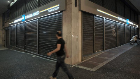 Un hombre camina delante de una sucursal cerrada del banco nacional de Grecia en Atenas./ EFE