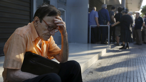 Giorgos, un jubilado de 77 años de edad, de Atenas, espera en la puerta de una sucursal del Banco Nacional de Grecia mientras junto con docenas de otros pensionistas, con la esperanza de obtener sus pensiones tras decretarse el corralito. C