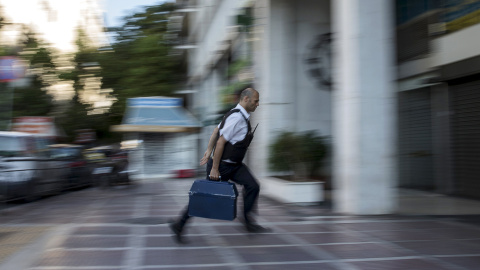 Un trabajador de seguridad lleva dinero a una sucursal del Banco Nacional en Atenas. REUTERS / Marko Djurica