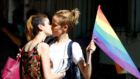 Dos participantesen la marcha en Estambul por los derechos de los transexuales en LGBT se besan sosteniendo una bandera arcoiris. REUTERS/Osman Orsal