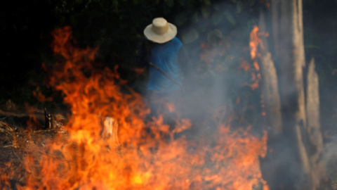 Un hombre trabaja en un tramo de la Amazonia en llamas. / Reuters