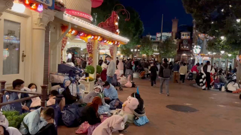 Visitantes de Disneyland en Shanghái, sentados en el suelo del parque temático a la espera de poder salir del recinto, a 31 de octubre de 2022.