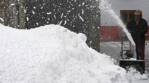 Un hombre quita nieve de las calles de Puebla de Lillo, en León, durante el temporal que afecta al norte de la provincia. / EFE