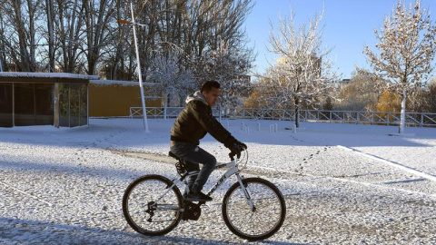 Un hombre se desplaza en bicicleta en medio del temporal de frío y nieve que afecta a León. / EFE