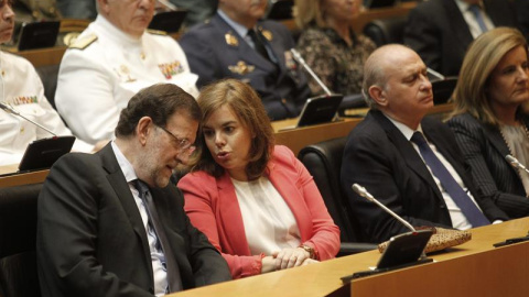 El presidente del Gobierno, Mariano Rajoy (i), conversa con la vicepresidenta, Soraya Sáenz de Santamaría, junto al ministro del Interior, Jorge Fernández Díaz (d), durante el acto que ha tenido lugar hoy en la Cámara Baja para rendir homen