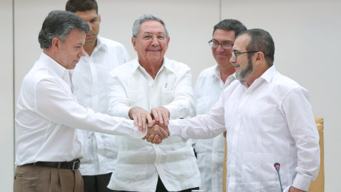 El presidente de Colombia, Juan Manuel Santos, se da la mano con el jefe de las FARC, Rodrigo Londoño 'Timochenko', en presencia del presidente de Cuba, Raúl Castro. - REUTERS