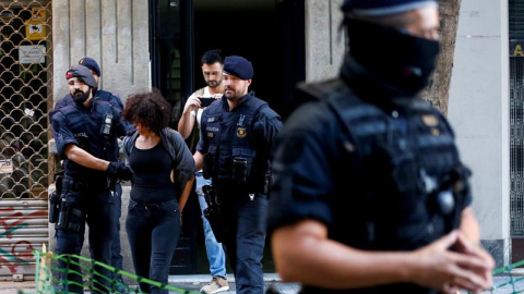 Mossos d'Esquadra trasladan a una persona detenida tras un operativo conjunto con la Guardia Urbana para desmantelar pisos convertidos en puntos de venta de droga en el barrio de Sant Antoni de L'Eixample y en el distrito de Sants-Montjuïc 