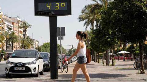 Una mujer camina junto a un termómetro que marca 43 grados en las calles de Córdoba. - EFE