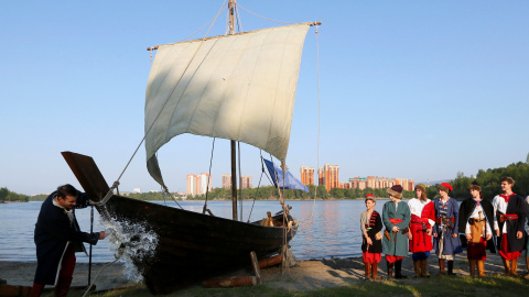 Un hombre rompe una botella de vino espumoso sobre el casco de una réplica de un antiguo barco velero ruso  durante la ceremonia de lanzamiento en una orilla del río Yenisei en Krasnoyarsk. REUTERS/Ilya Naymushin-