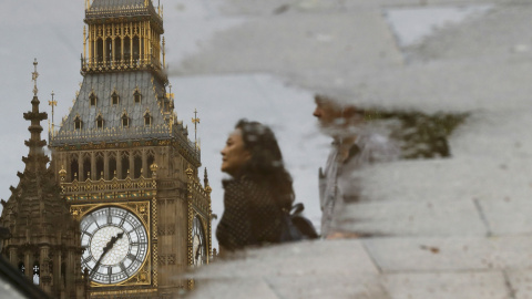 Personas reflejadas en un charco caminando junto al Parlamento londinense. REUTERS / Stefan Wermuth