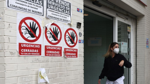 Una sanitaria con mascarilla en la puerta del Centro de Salud Ángela Uriarte, donde hay carteles de protesta que rezan 'Urgencias Cerradas, tu salud vendida', a 21 de octubre de 2022, en Madrid.