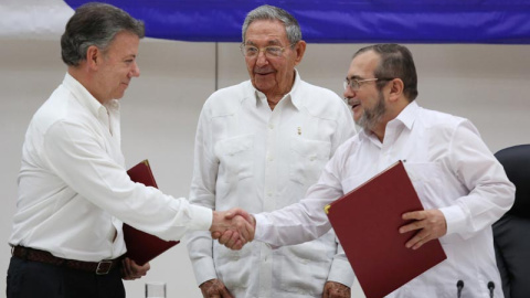 De izquierda a derecha, Juan Manuel Santos, presidente de Colombia, estrecha la mano del líder guerrillero Rodrigo Londono, más conocidad por su nombre de guerra, 'Timochenko'. Todo ello ante el presidente de Cuba, Raúl Castro. / REUTERS