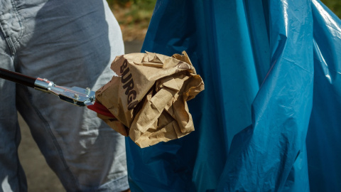 Un hombre tira un envoltorio de comida a la basura.