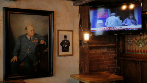 A painting of former British Prime Minister Winston Churchill hangs beside a television broadcasting Brexit polling at The Churchill Tavern, a British themed bar, on the day Britain votes whether or not to remain in the European Union, in t