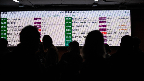 Imagen de archivo de varias personas observando la pantalla de horarios de los trenes en una estación de Madrid.