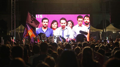 Simpatizantes de Unidos Podemos escuchan las declaraciones de su líder Pablo Iglesias (c. en la pantalla) durante su comparecencia ante la prensa tras conocer los resultados de las elecciones generales celebradas en España, hoy en la plaza 