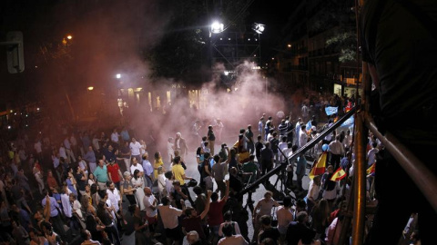 Varias personas disfrazados de presos lanzan botes de humo en los alrededores de la calle Génova de Madrid./ EFE