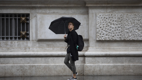 Una mujer se protege de la lluvia bajo su paraguas.