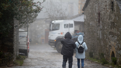 Dos personas pasean abrigadas por una calle de Pedrafita do Cebreiro, en Lugo, a 13 de diciembre de 2023.