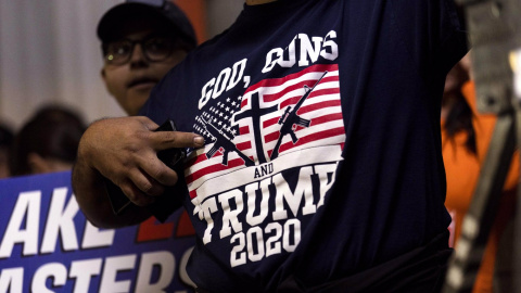 Un simpatizante republicano señala a su camiseta que dice "Dios, armas y Trump 2020", durante un mitin  en Schnepf Farms en Queen Creek, Arizona (EEUU). EFE/Etienne Laurent