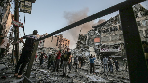 Un grupo de palestinos inspeccionan los restos de una torre destruida por un bombardeo israelí.