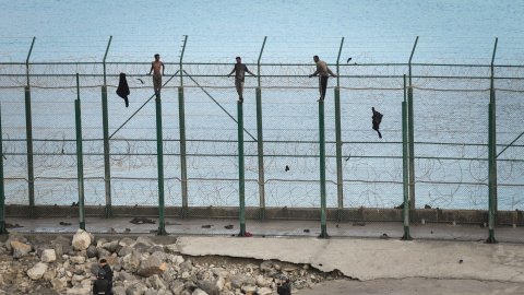 30/08/2019 - En la imagen, tres de un total de 153 migrantes, entran en Ceuta saltando su doble valla en la primera incursión en grupo en un año / EUROPA PRESS