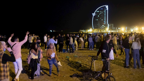 15/05/2021. Varios jóvenes recogen sus pertenencias en la playa de la Barceloneta mientras la Policía desaloja la zona, este sábado en Barcelona. - EFE