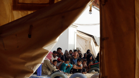 Refugiados sirios esperan para subir a un vehículo militar de Jordania tras conseguir cruzar la frontera norte entre ambos países con sus familias. REUTERS/Muhammad Hamed