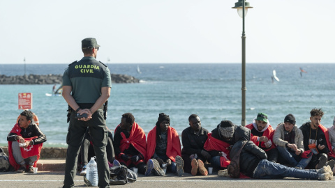 Un agente de la Guardia Civil custodia a un grupo de personas migrantes llegadas en patera a la costa de Teguise, en Lanzarote, a 26 de diciembre de 2023.