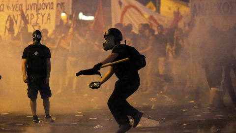 Los manifestantes iban preparados con máscaras antigas. En la imagen, uno de ellos arroja un proyectil incendiario a la policía. EFE/ Yannis Kolesidis